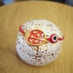 Μαρτάκι με μεταλλική μεγάλη πασχαλίτσα και κόκκινο ματάκι.