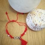 Μαρτάκι με ασημί μεταλλικό στοιχείο άπειρο και κόκκινες και λευκές χάντρες.